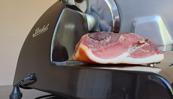 Koud gerookte rauwe ham met lichte rooksmaak, dunne plakjes op een serveerplank