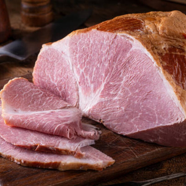 A delicious naturally smoked ham on a rustic wood cutting board.